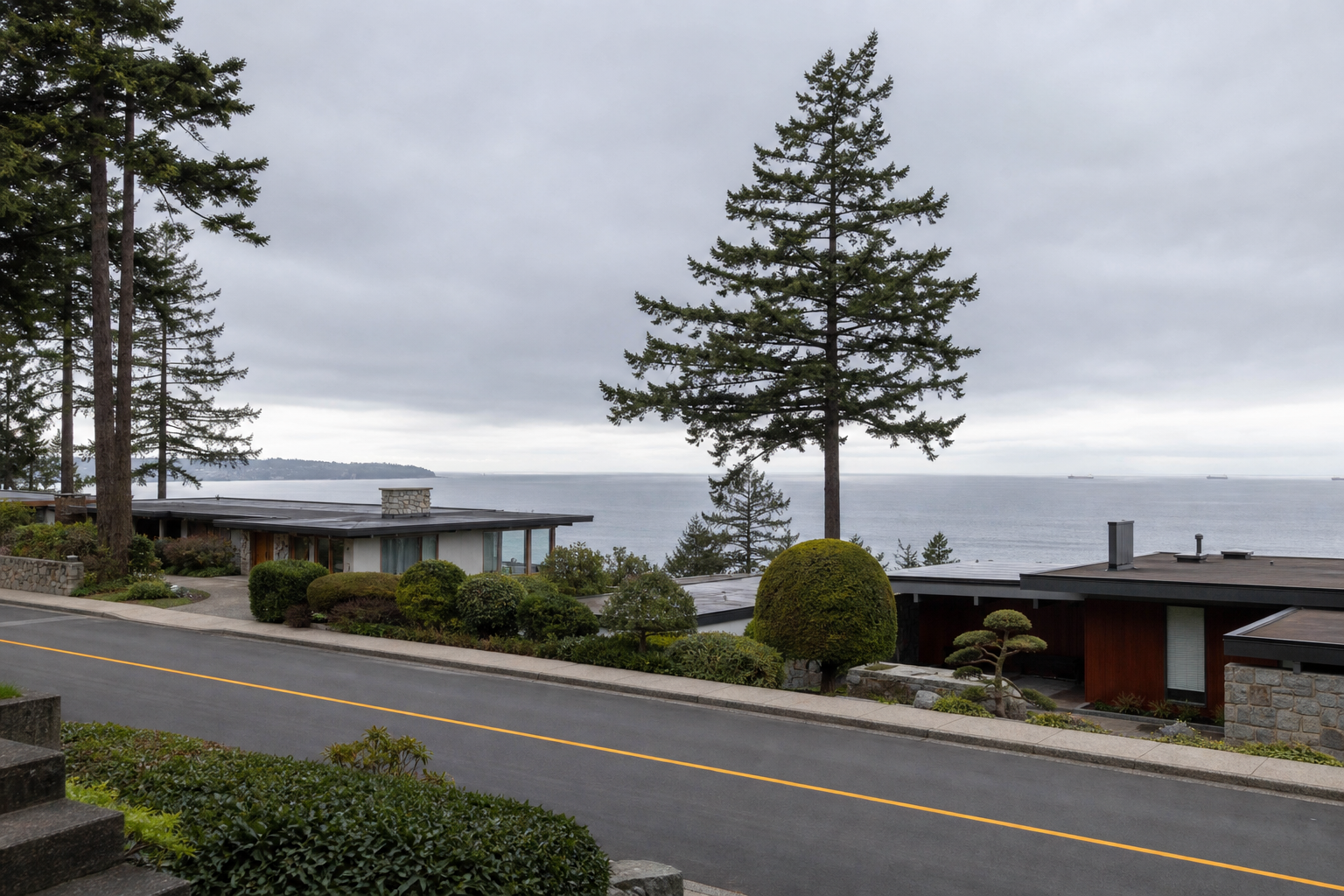 A 1960s post-and-beam house in West Vancouver with full-height glazing onto Howe Sound, large cedar beams crossing the great-room ceiling